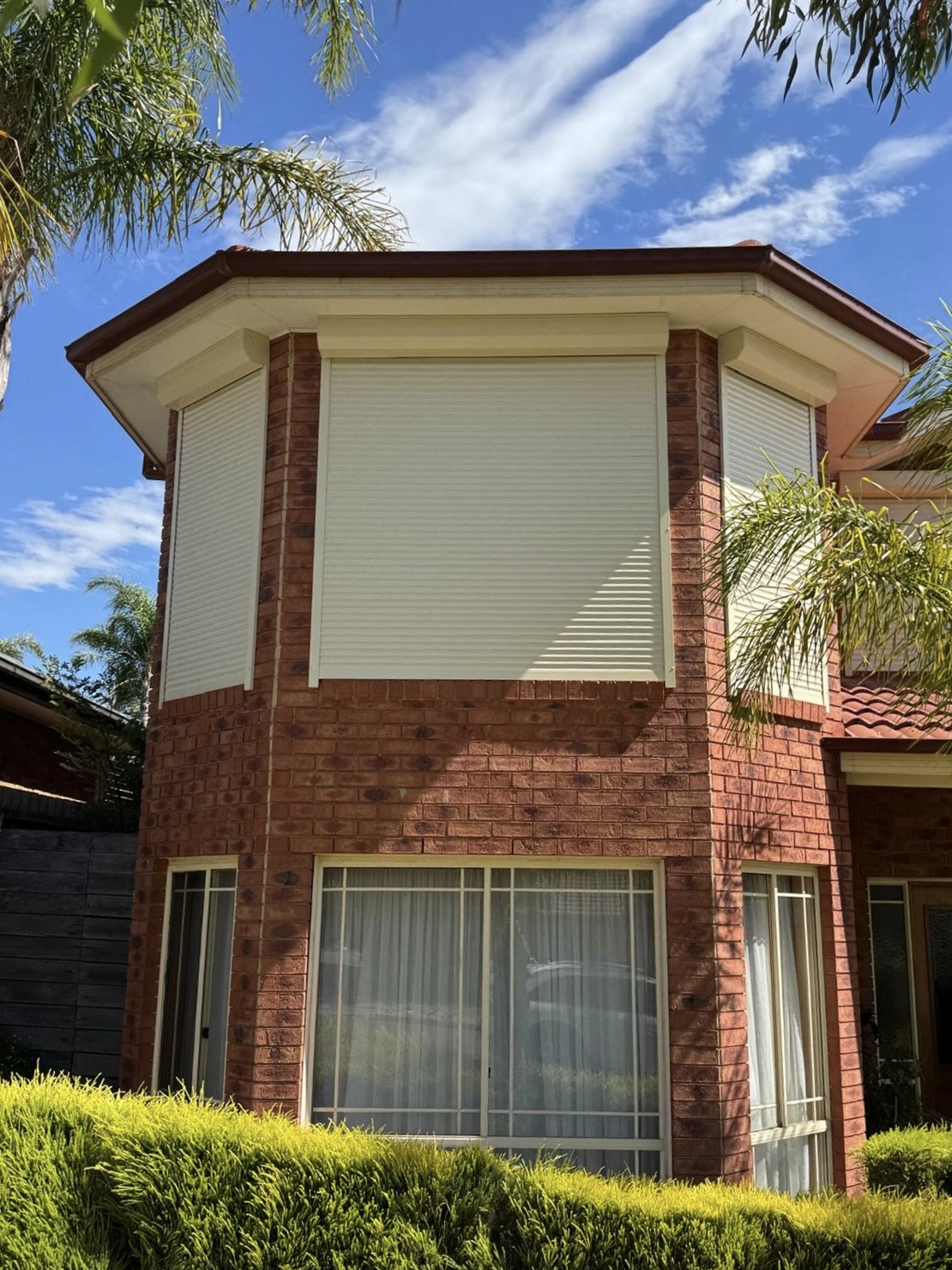 White roller shutters on two-storey brick home