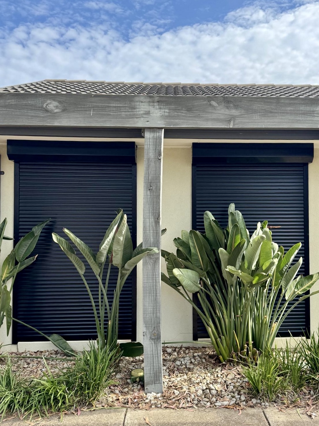 Black roller shutters with tropical garden