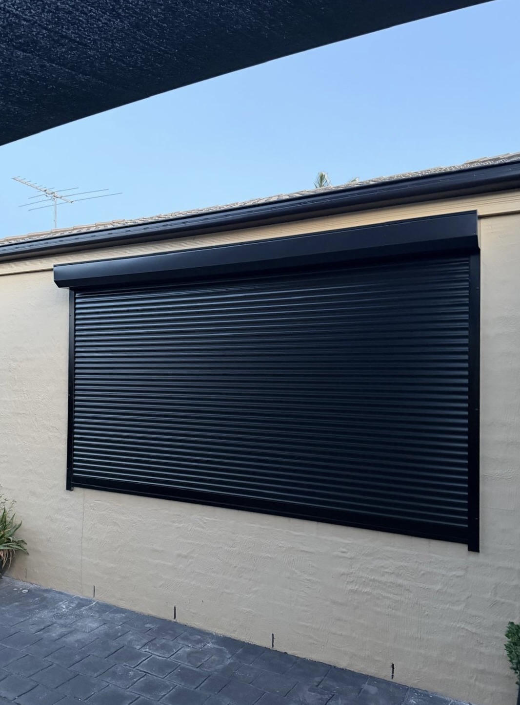 Large black roller shutter on render wall